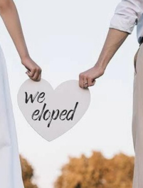 We eloped wedding sign held by married couple
