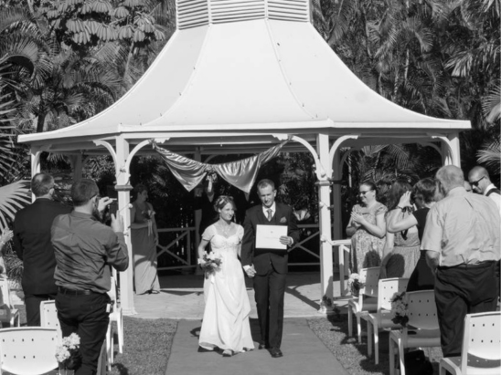 Married couple walking down aisle with wedding certificate in Townsville with marriage celebrant Amanda Medill