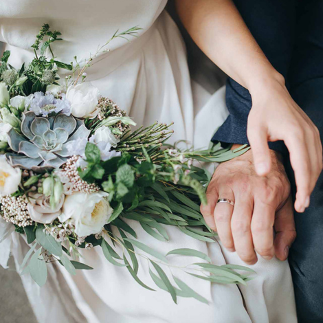 Husband and wife holding hands with wedding flowers
